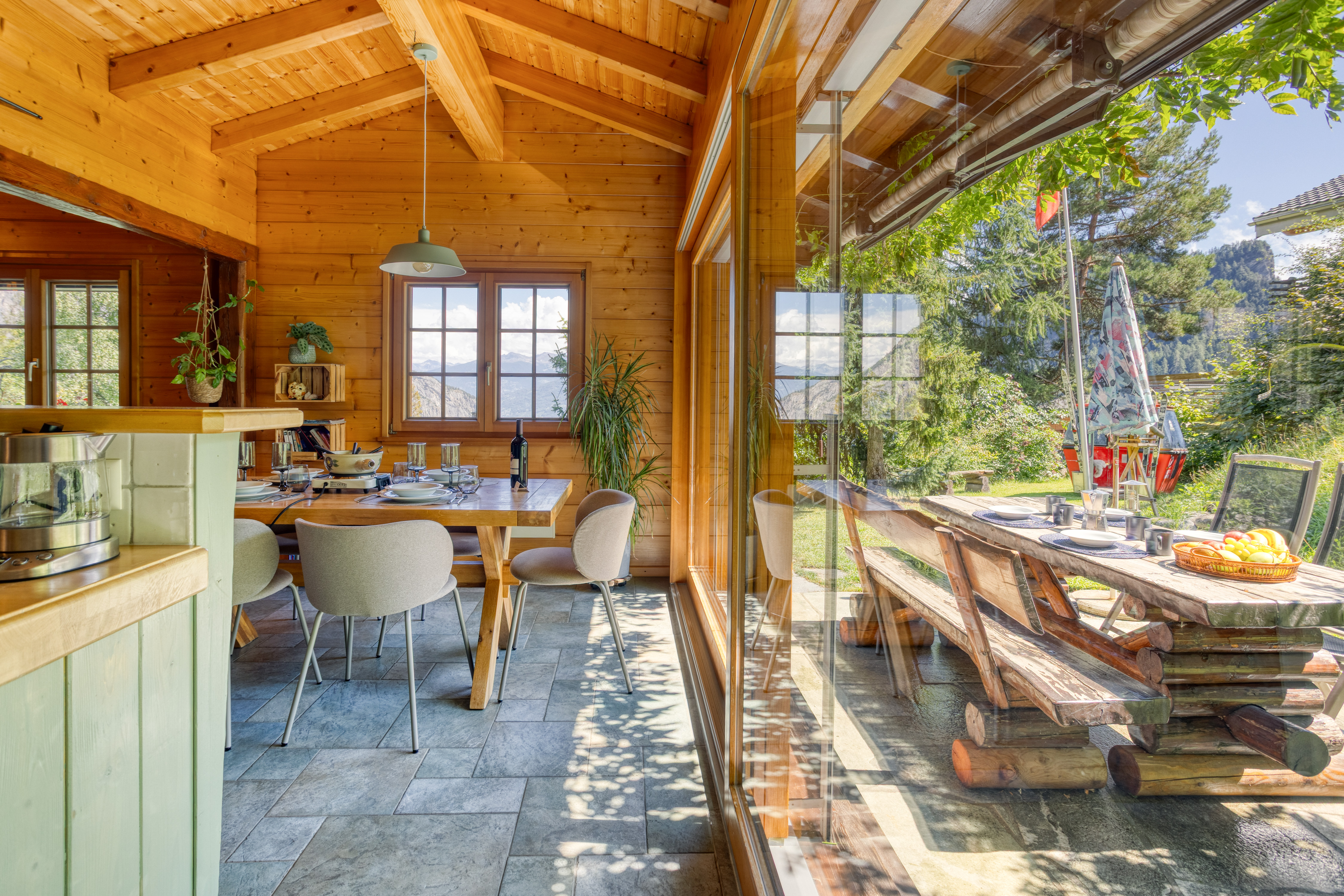 Salle à manger lumineuse du chalet Mon Rêve avec baie vitrée ouverte sur la terrasse