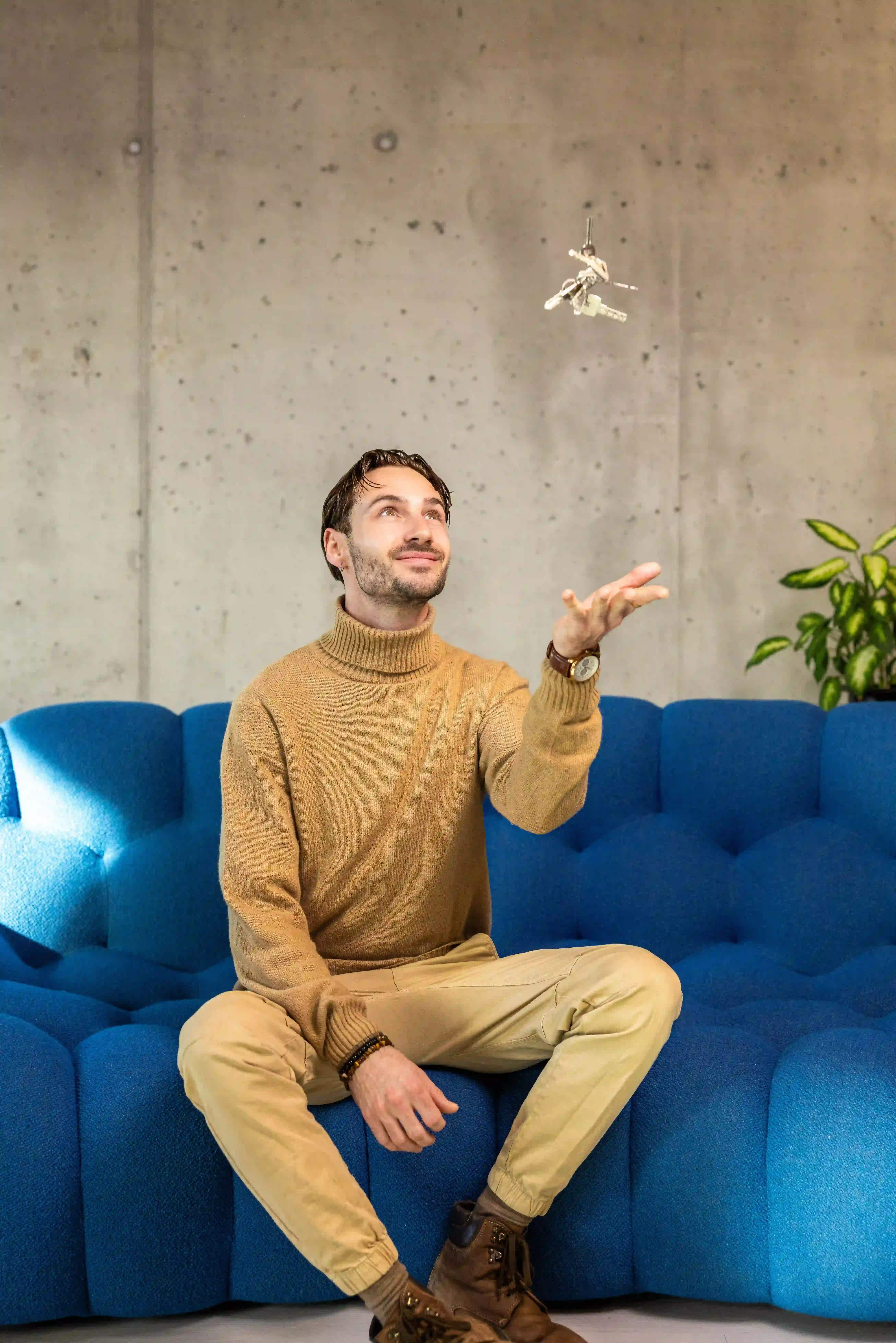 Tim, membre de l’équipe, assis sur un canapé lançant un jeu de clés en l’air et regardant vers elles